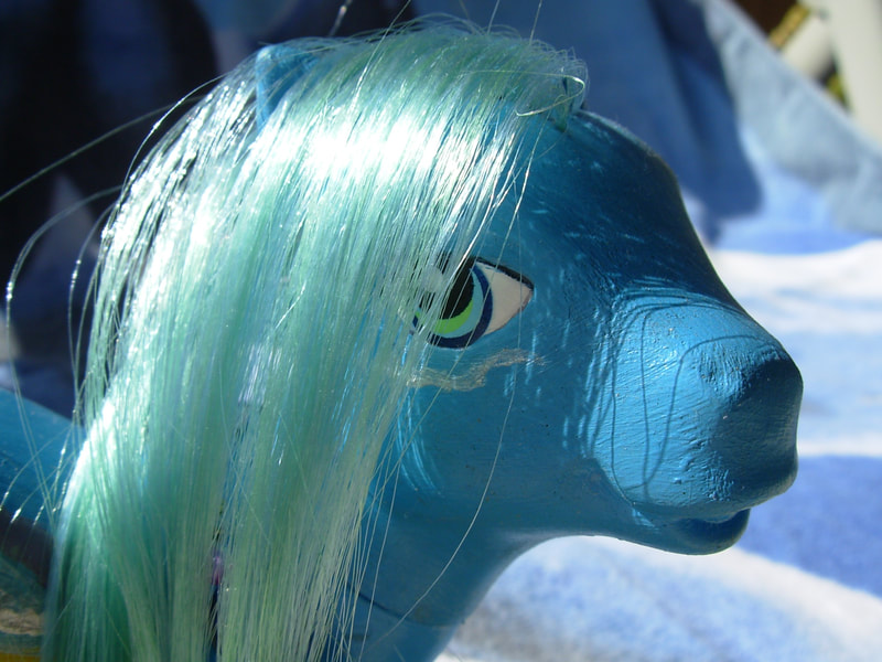 A teal-blue gradient G3 MLP with pale green hair, blue-green eyes, a silver wave cheek tattoo