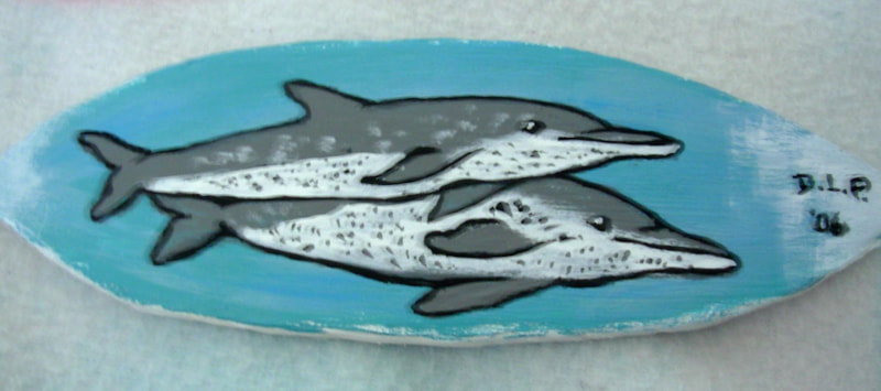 A handmade surfboard with dolphins on one side