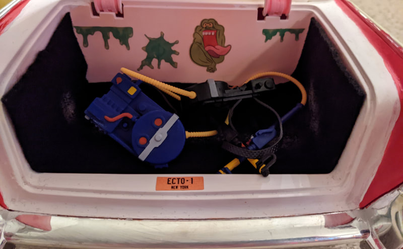The open trunk of the Ecto-1, with Janine and Spengs' proton packs inside